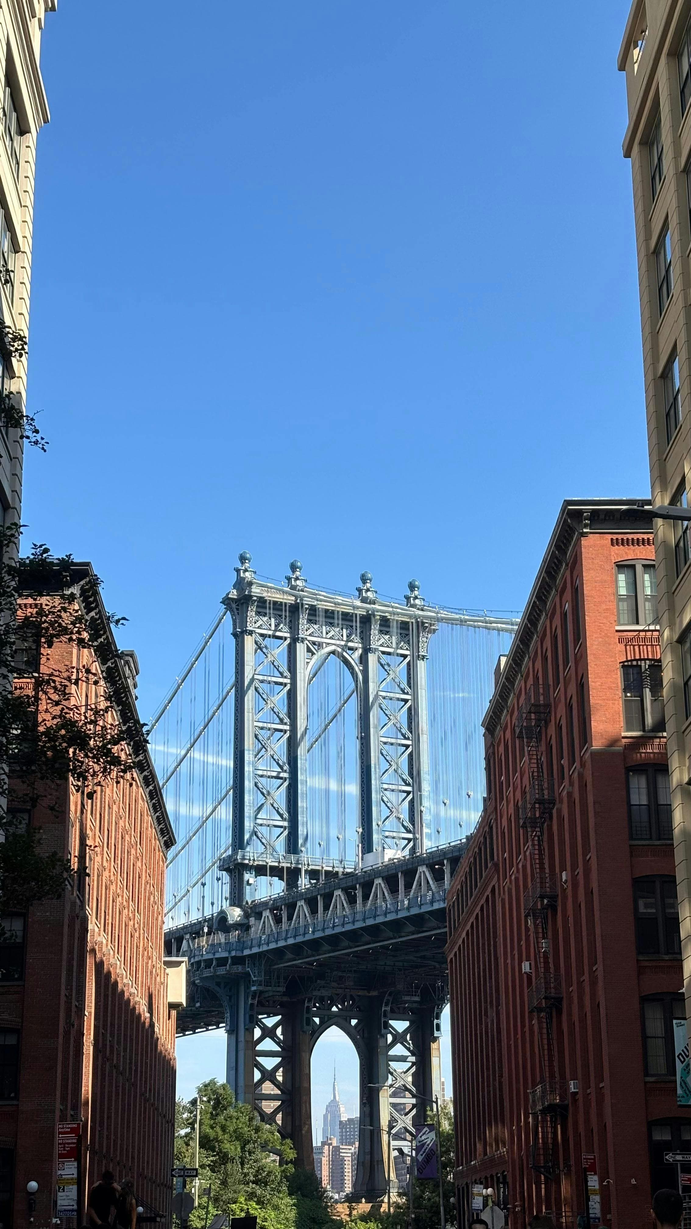Manhattan Bridge in daylight framed by red-brick buildings